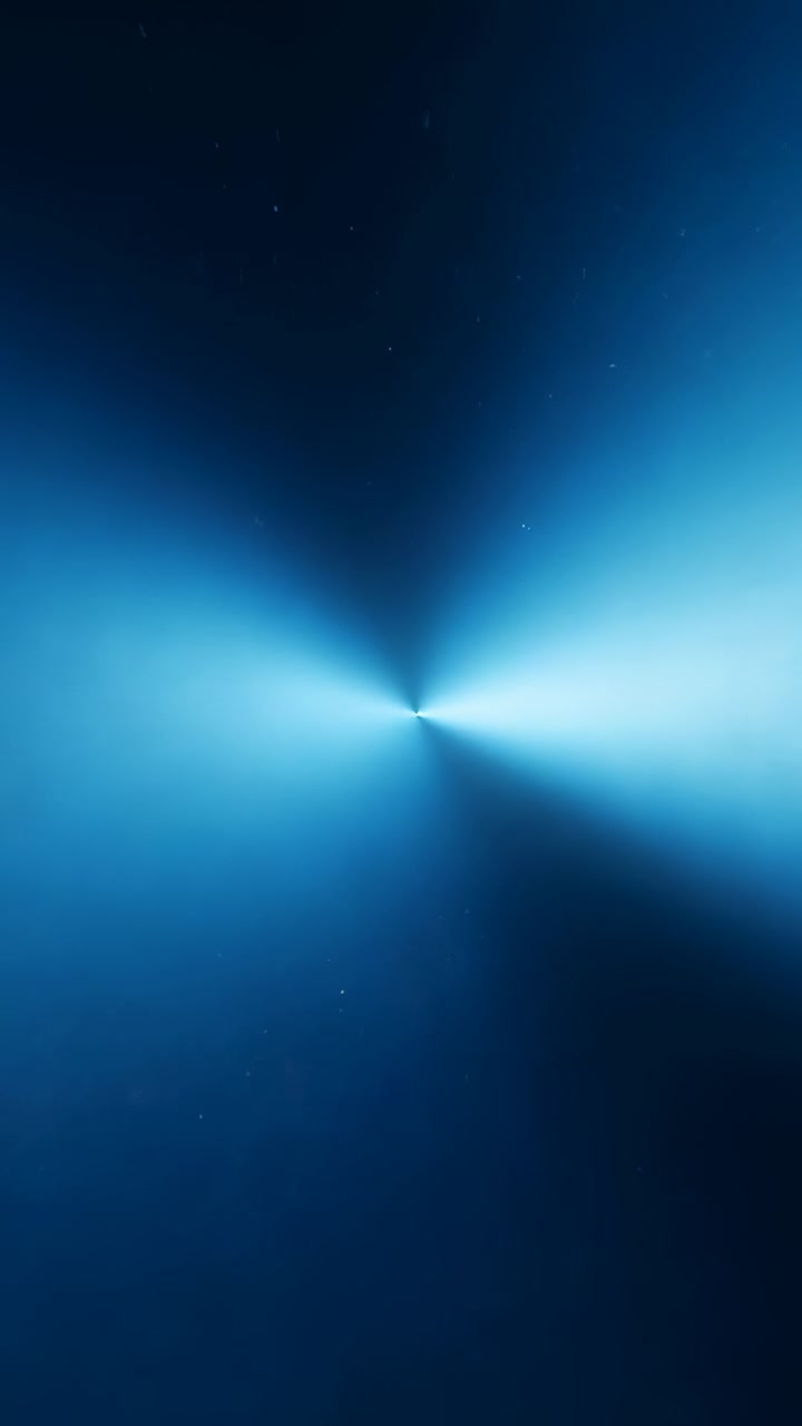Vertical video: Pulsing central flare rotating beams in abstract as frames shift with faint specks