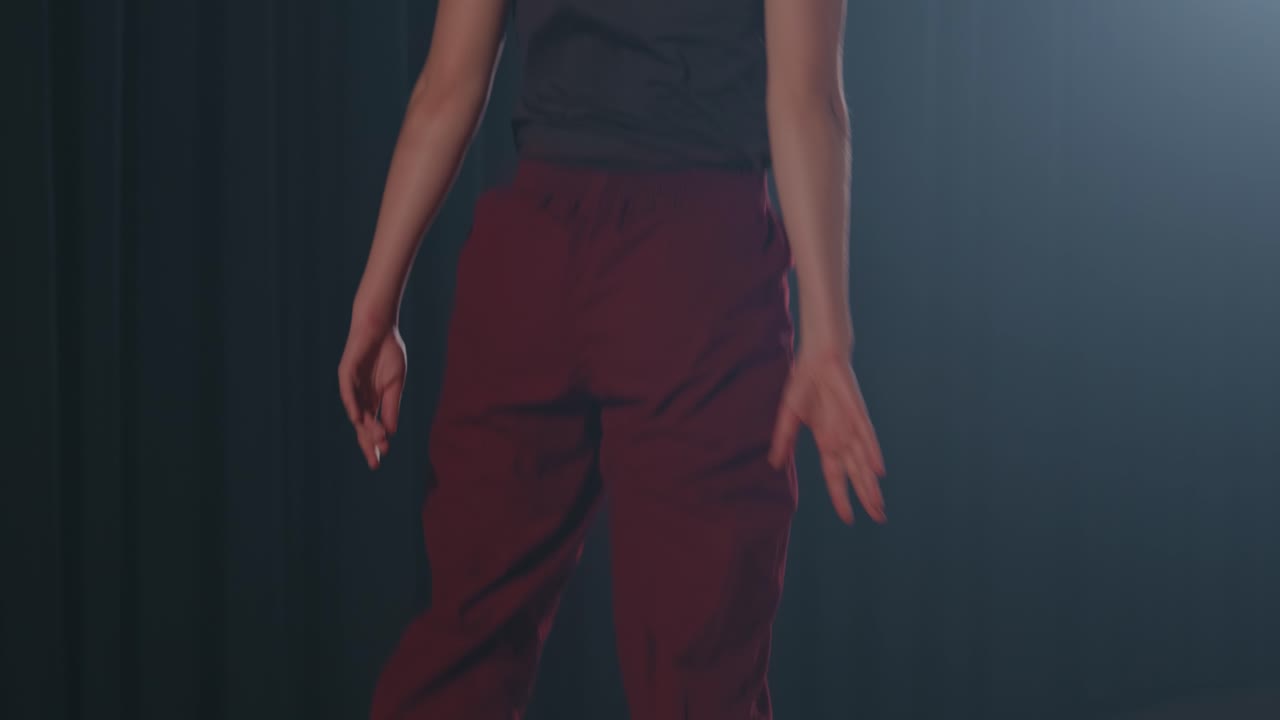 Woman dances energetically on stage with dramatic lighting and theatrical background