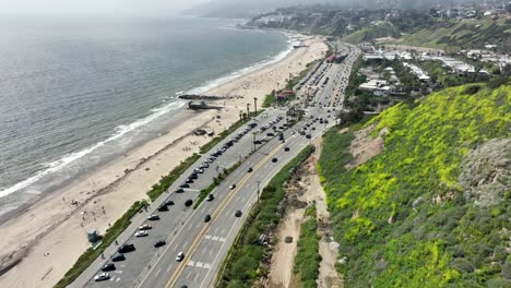 Pacific-Palisades-with-cars-on-Pacific-Coast-Highway,-aerial-flyover