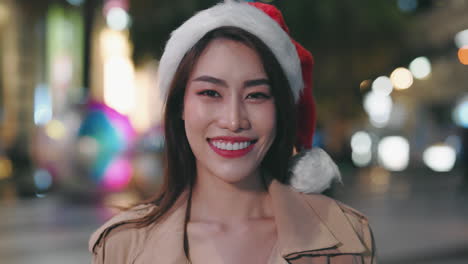 woman wearing santa hat in city at night