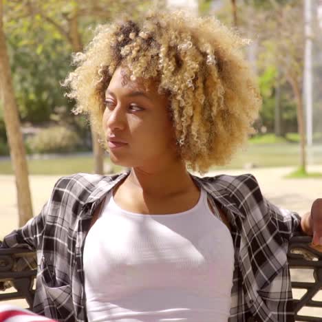 young woman relaxing on park bench on sunny day