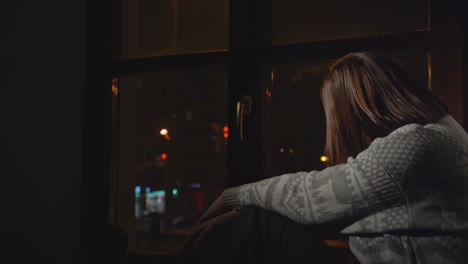 woman sitting by window at night