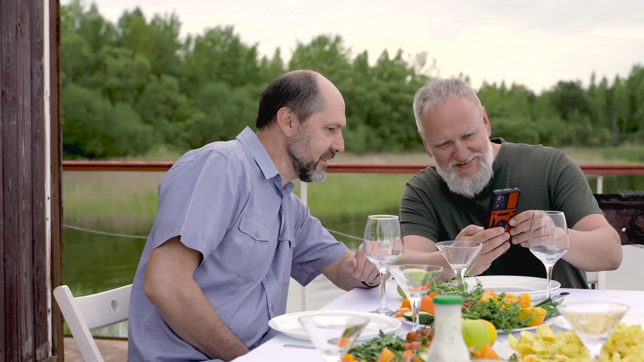 Dois homens jantando ou almoçando ao ar livre.