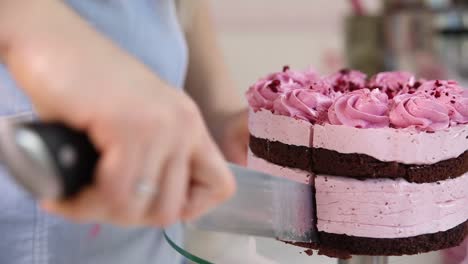 mujer cortando un hermoso pastel de frambuesa rosa