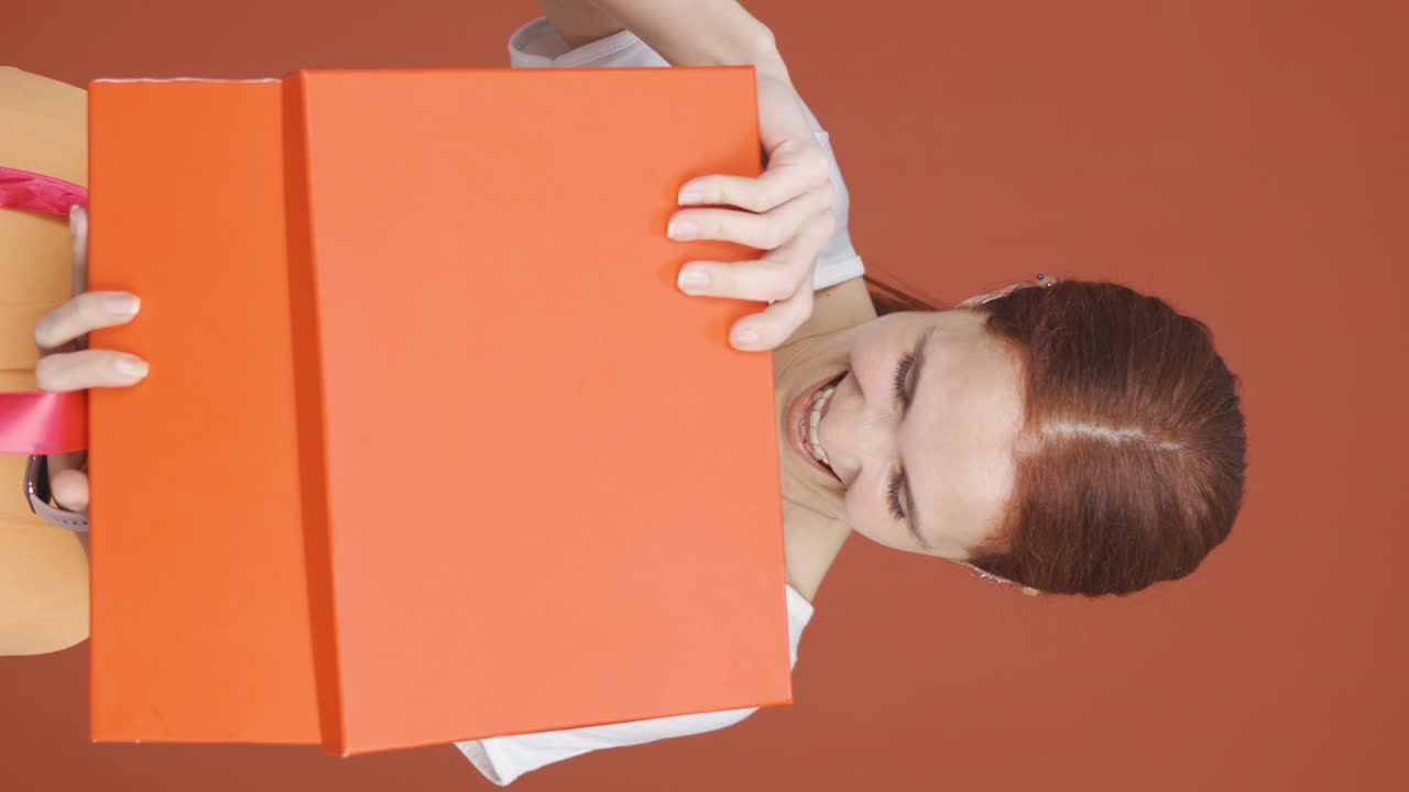 Video vertical de mujer feliz y alegre abriendo un paquete de regalo