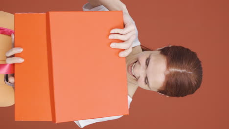 video vertical de una mujer feliz y alegre abriendo un paquete de regalos.