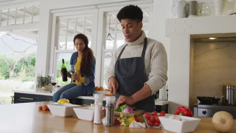 video of happy biracial couple preparing meal together and drink wine