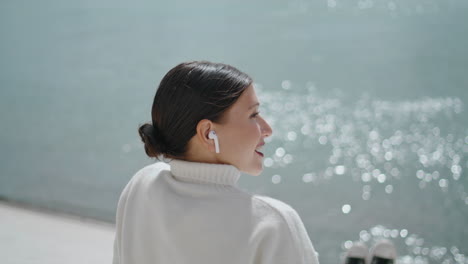 young woman speaking wireless earphones sitting quay at weekend closeup vertical