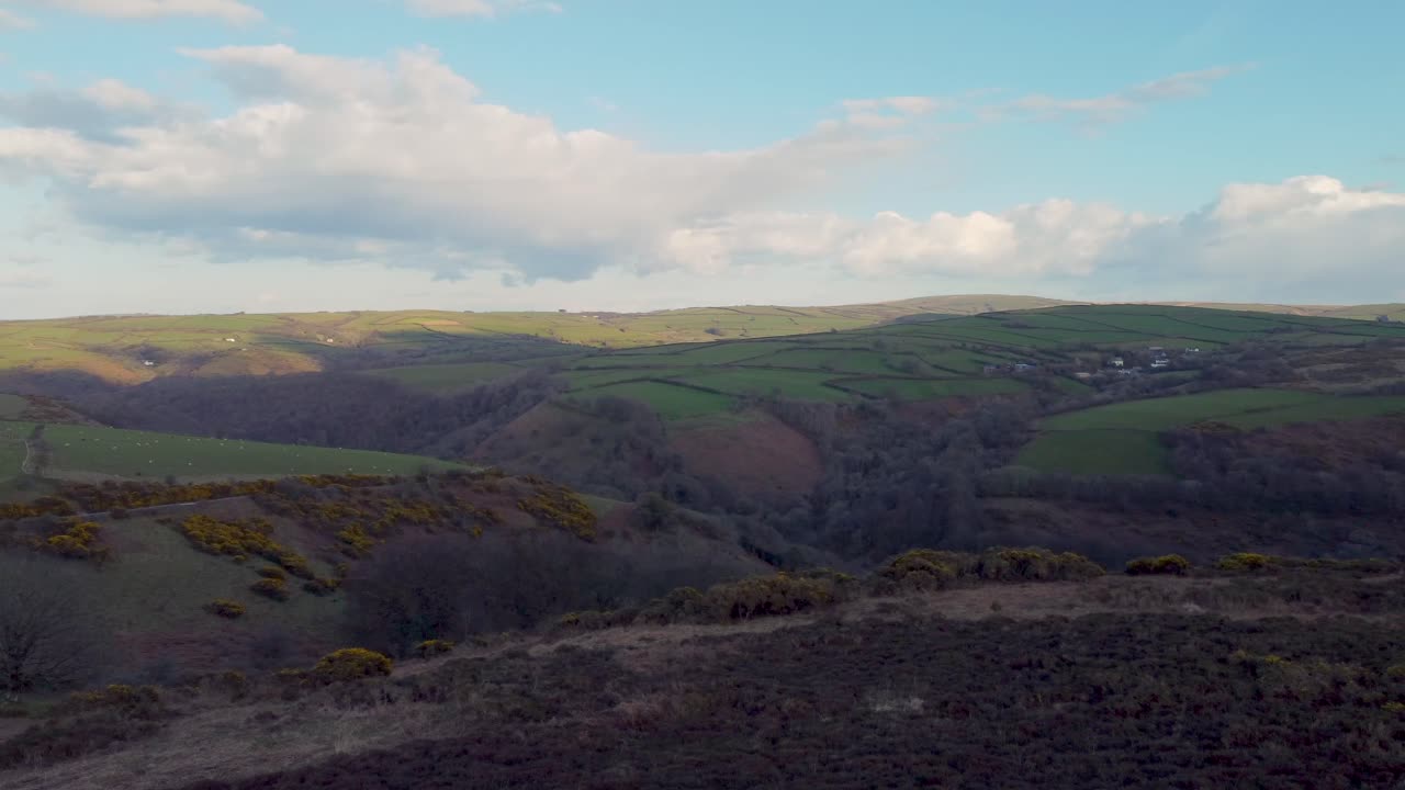 fotografía panorámica sobre páramos y campos verdes con nubes y cielo azul brillante en north devon, reino unido