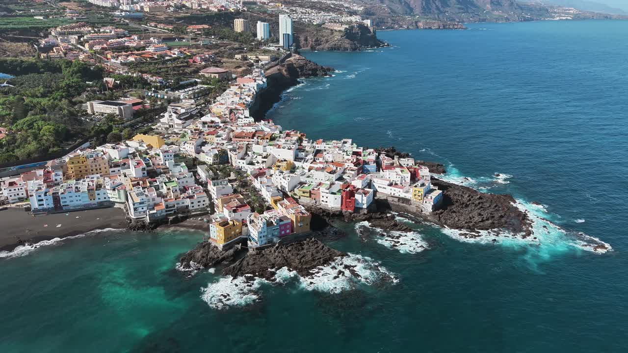 Aerial coastal view of Punta Brava settlement built on rocky shores surrounded by deep blue Atlantic Ocean waves, Tenerife, Canary Islands, Spain