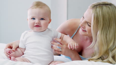 mother playing on bed at home with baby son