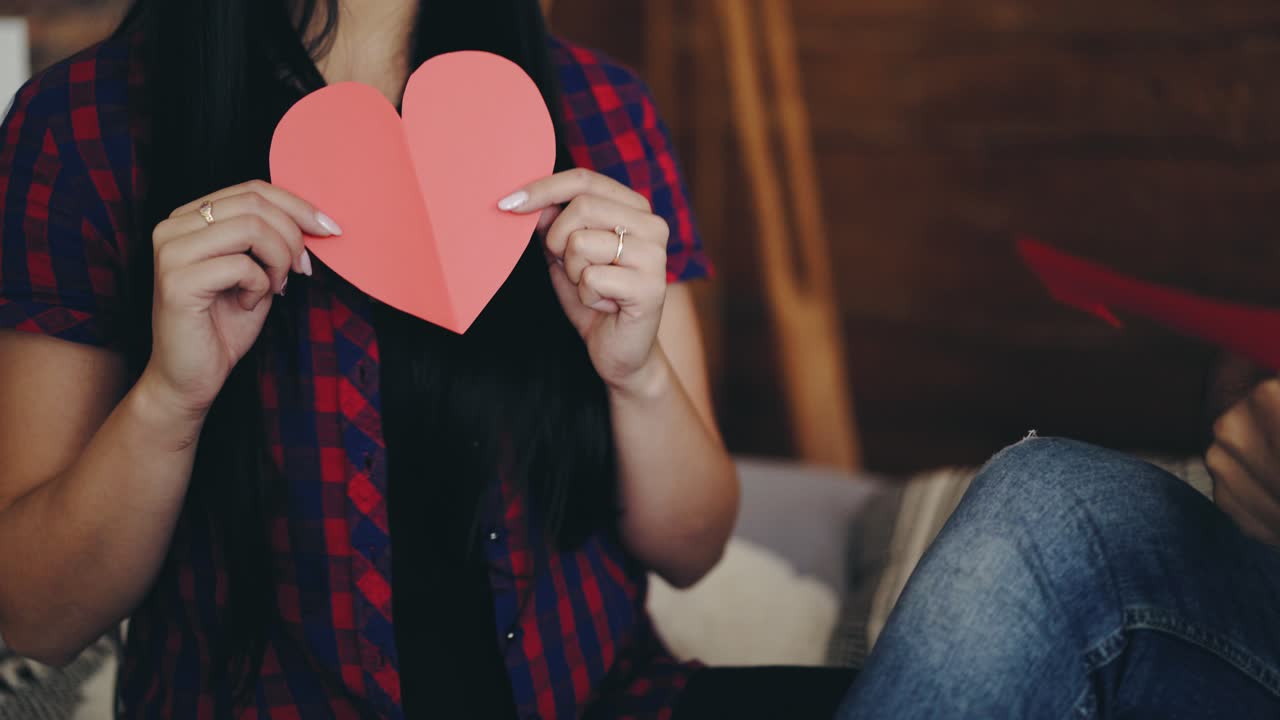 girl is showing ready carved heart from colored paper for Valentine's Day