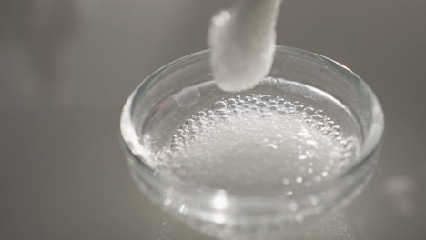 white gel bubbles gently lifted by silicone brush in glass bowl to test texture and consistency under soft light, highlighting skincare prep, sensory detail and professional facial treatment ritual