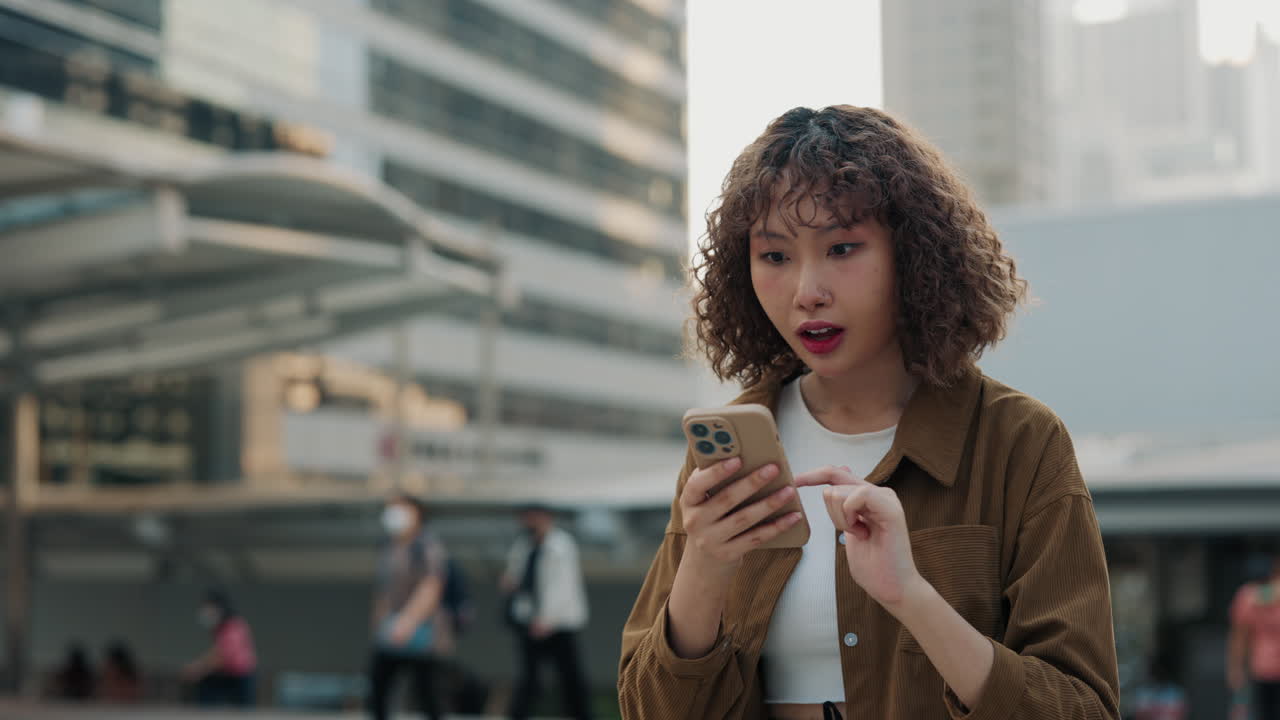 Young Woman Reacts to Phone on City Street