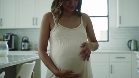 a glimpse into motherhood: an expecting woman tenderly touches her baby bump in a bright and inviting kitchen space
