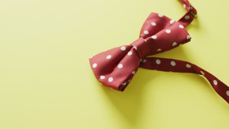 video of red dotted bow tie lying on yellow background