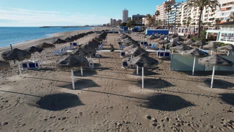 Drone-footage-straw-umbrella-sunbed-at-Fuengirola-resort-beach-with-boats