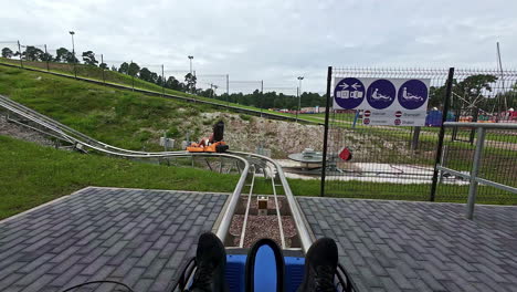 person on small fun fair roller coaster ride watches as person ahead starts moving