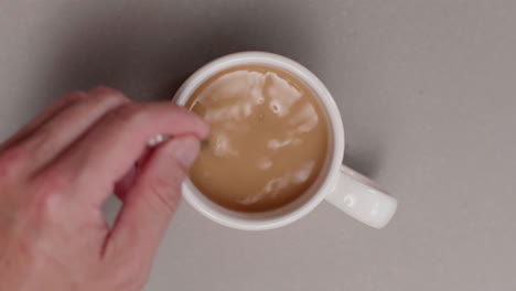 stirring coffee or tea in a white mug
