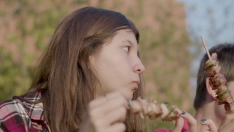 close-up of happy teenage girl and preteen boy enjoying shashlik