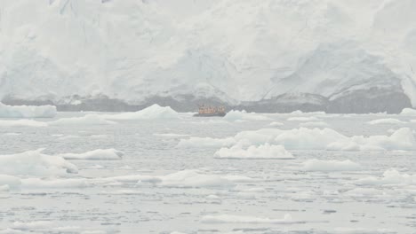 boat in distance in front of big glacier and harsh snow storm