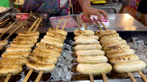 bananas grilling over charcoal at a market stall