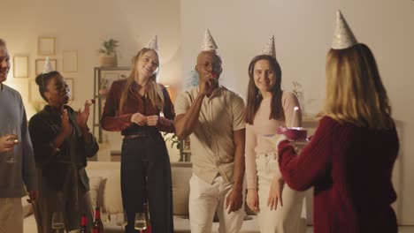 group of friends in birthday party, girl blows out a candle on the birthday cake making a wish 1