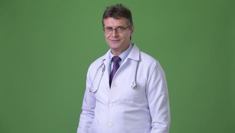hombre maduro y guapo médico contra fondo verde