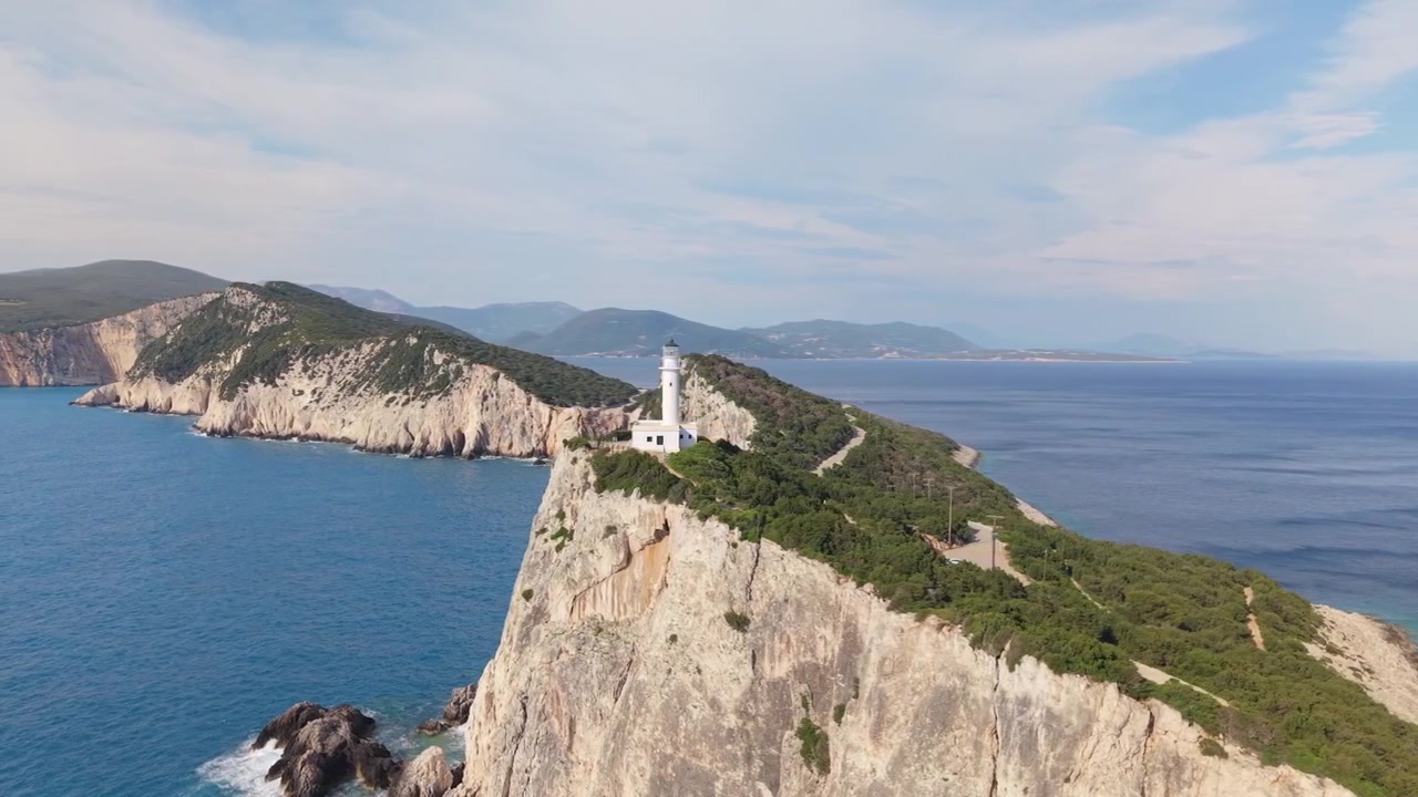 Sorvolo di drone del Faro di Capo Lefkatas arroccato su scogliere marine drammatiche sopra il Mar Ionio a Lefkada, Grecia. Paesaggio costiero mozzafiato, acqua blu e paesaggio mediterraneo