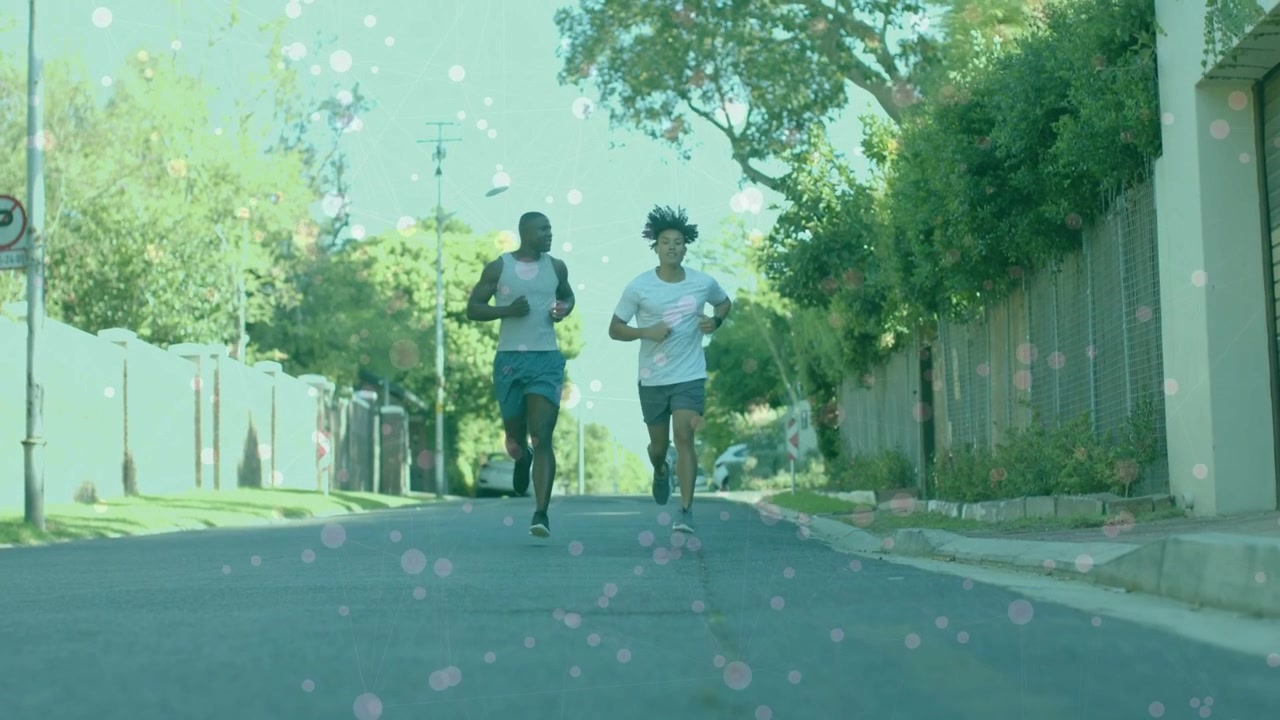 Due corridori maschi iniziano a correre in discesa verso la telecamera per il fitness, con una leggera sovrapposizione bokeh fluttuante.