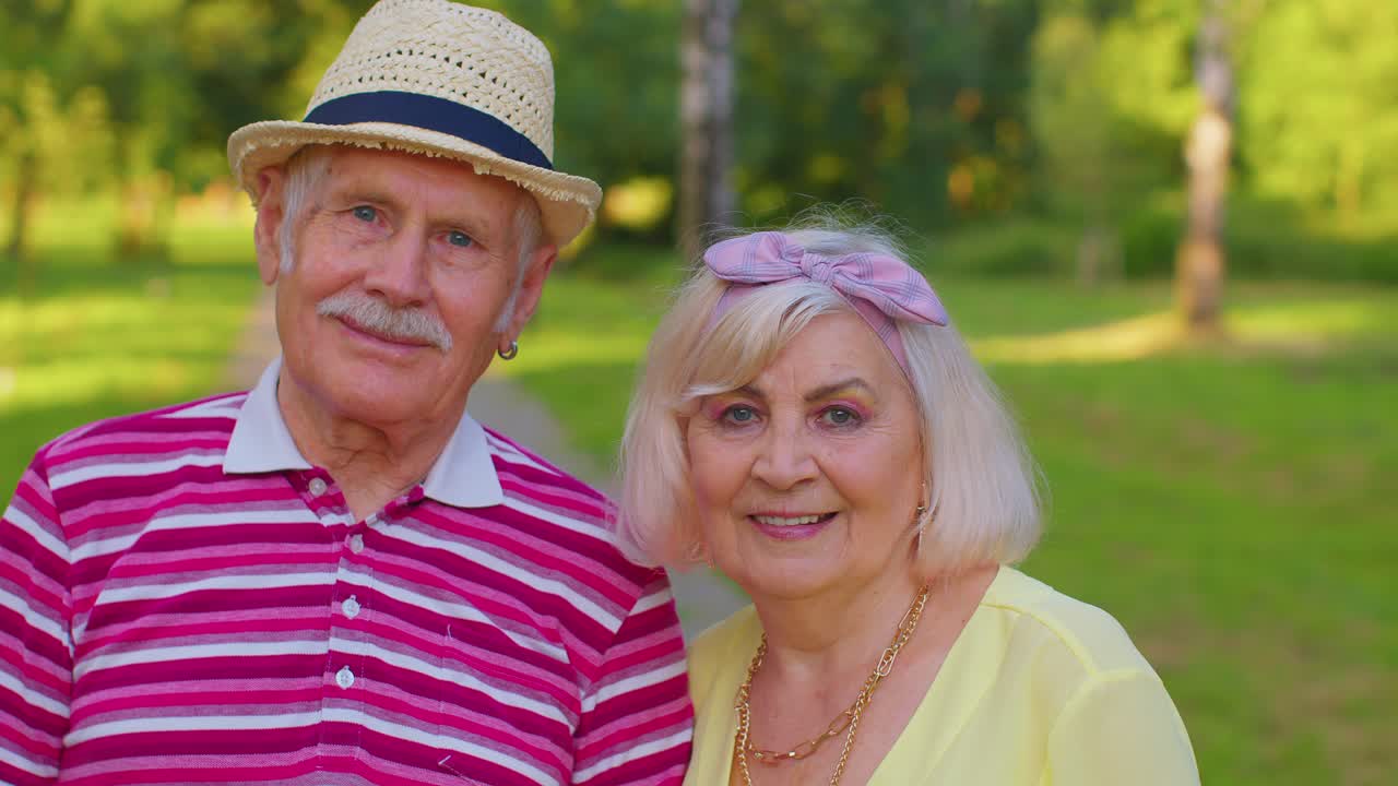 Coppia di anziani pensionati eleganti, nonna e nonno, che camminano, godendosi il tempo insieme nel parco