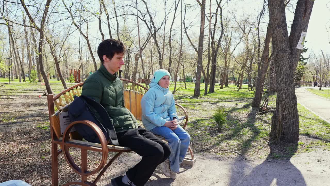 Giovane uomo e bambino seduti su una panchina del parco in una soleggiata giornata di primavera