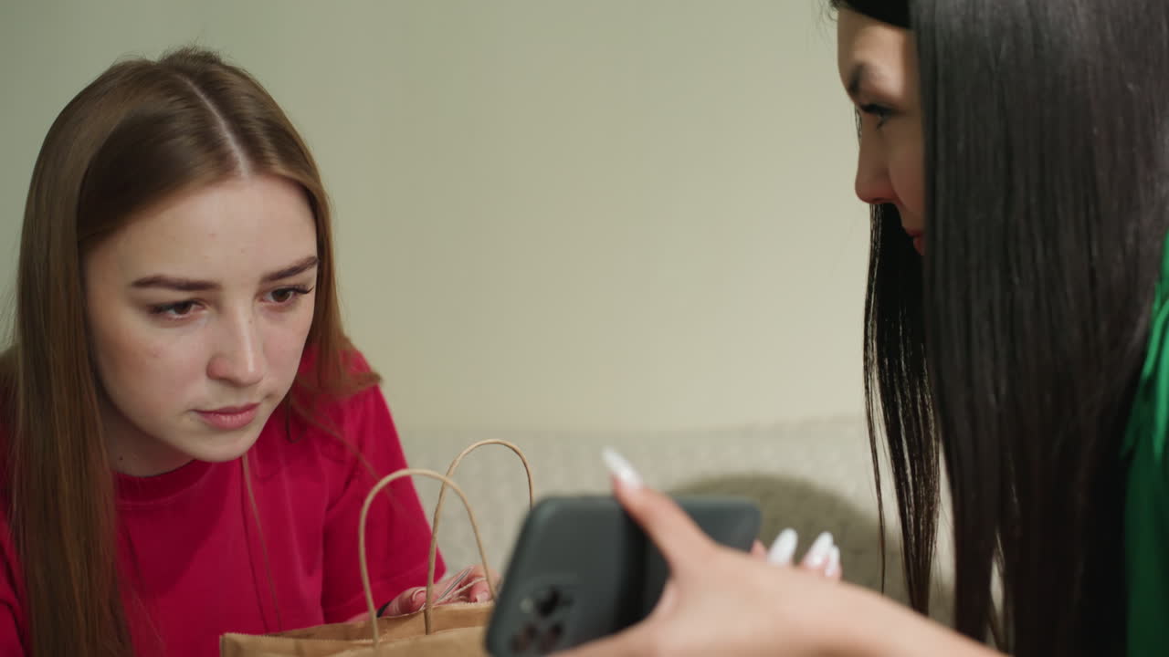 primer plano de una prueba de altavoz en un ambiente acogedor; un amigo observa cómo una mujer evalúa la calidad del sonido y el volumen; escena en interiores donde una mujer evalúa un altavoz portátil con un amigo mirando atentamente