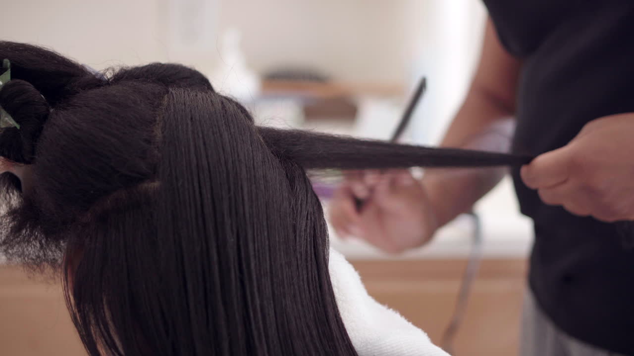 미용실에서 아름다운 헤어스타일을 만들기 위해 빗을 사용하여 흑인 여성의 머리 부분이나 자물쇠를 분리합니다.