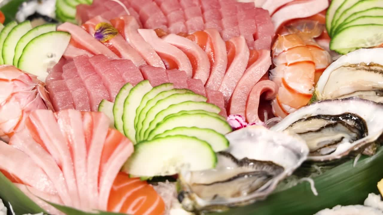 A close-up view of assorted sushi and oysters with cucumber slices and decorative flowers.
