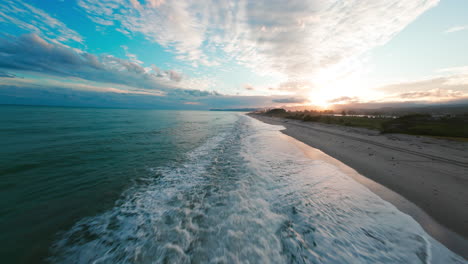 sea waves crash on the beach after a relaxing sunset in nature aerial