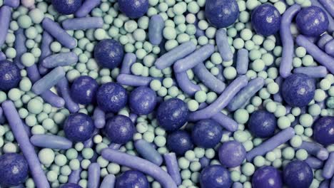 macro view of purple and green sprinkles rotating, showcasing texture and color in a vibrant, detailed composition