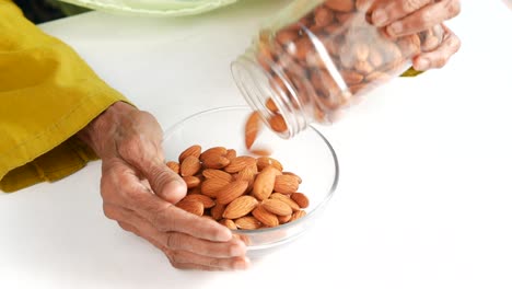 elderly person pouring almonds into a bowl