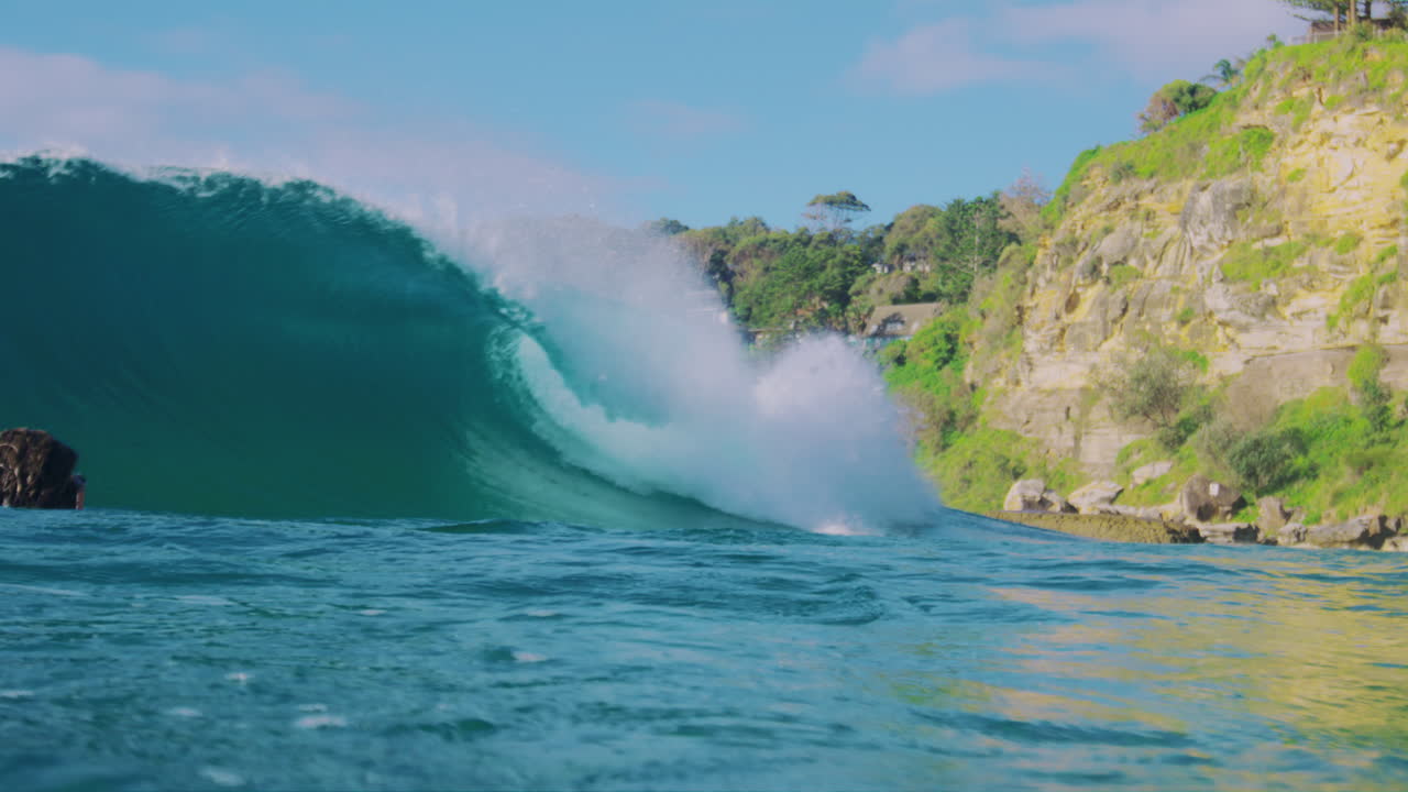 Slow motion view of surfer in the morning as surfer dives into back of wave crashing in front of photographer