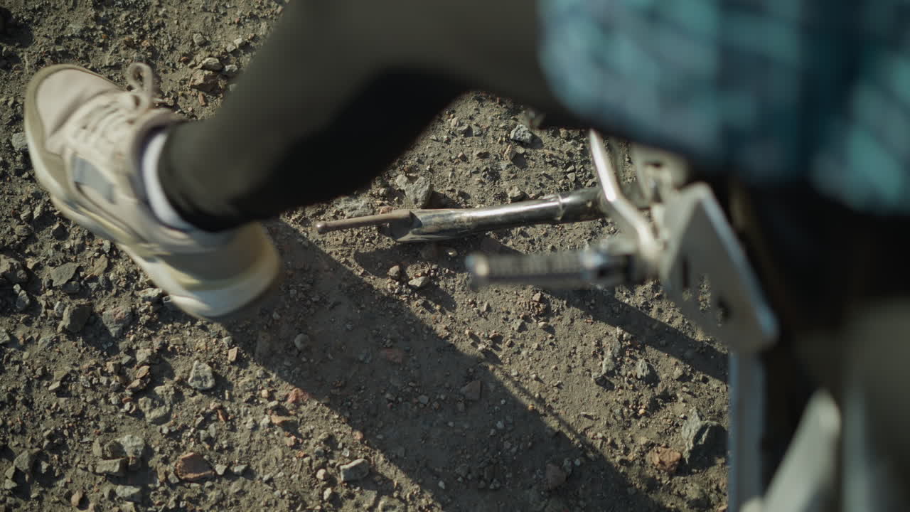 primer plano de un motociclista dejando caer el soporte de la bicicleta para equilibrarla en una superficie de grava
