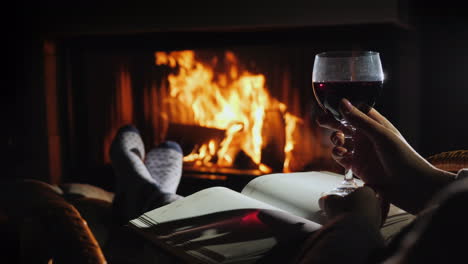sentado junto a la chimenea con un cuaderno en blanco y una copa de vino - planeando un nuevo concepto de vida