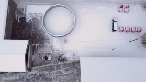 homeowner sweeping away snow in backyard after snowstorm in st constant, quebec, canada. birds eye view