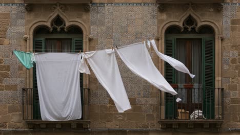 a serene moment captured between two frames, showcasing a beautiful display of white linens hanging gracefully from a balcony, with intricate architecture in the background