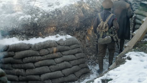 A-snow-covered-First-World-War-tench,-two-cold-unrecognisable-British-WW1-army-soldiers-walk-back-from-the-front-line-in-France