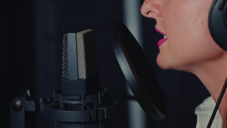 mujer cantando en un micrófono en un estudio de grabación