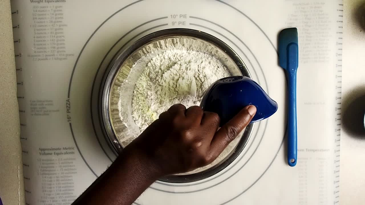 Overhead view of hands putting salt and yeast in the flour to make bread
