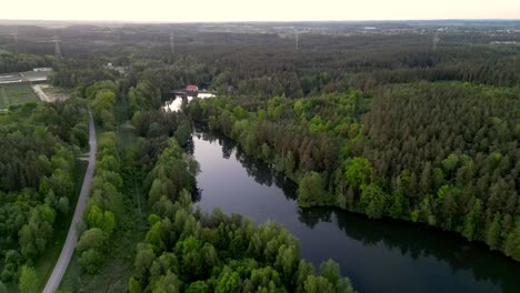 Panorama-after-sunset,-landscape-featuring-a-river,-forest,-and-a-road-winding-through-the-trees