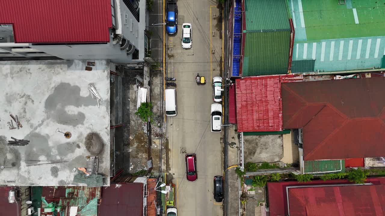 Streets in Manila with vibrant red and rusted rooftops, cars, and pedestrians. Manila, Philippines