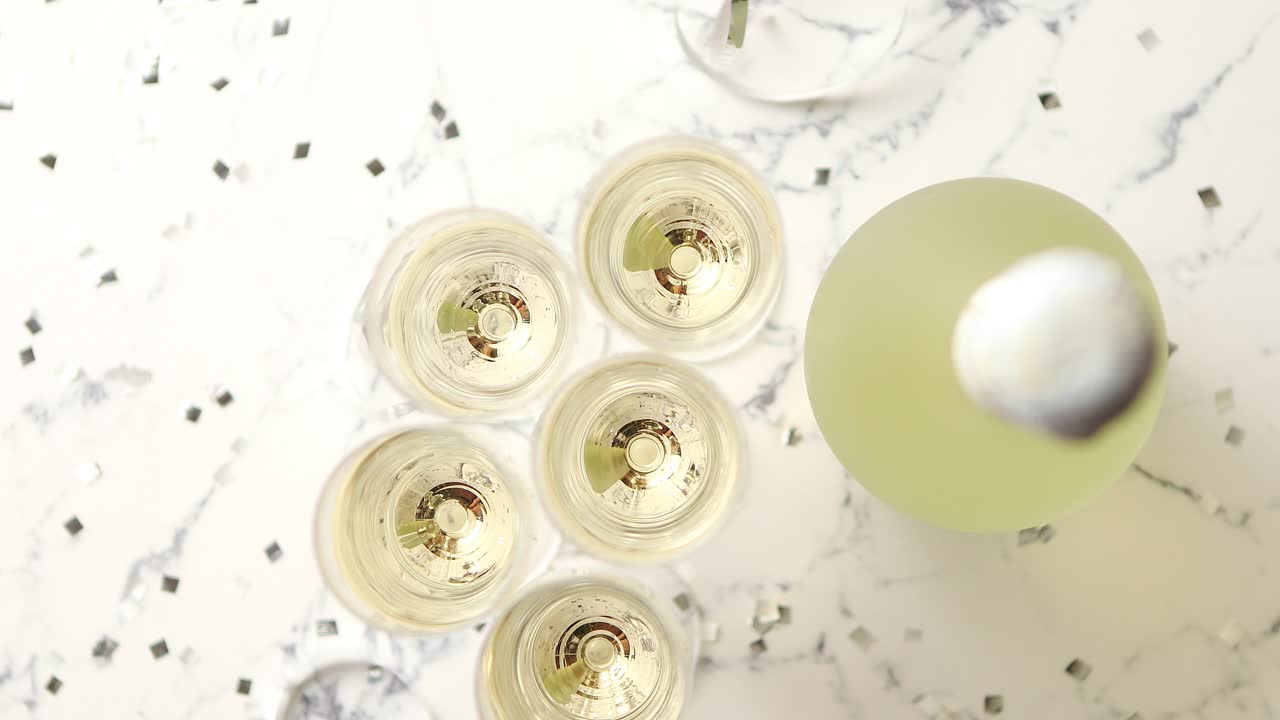 Bicchieri da champagne e bottiglia posti su sfondo di marmo bianco.