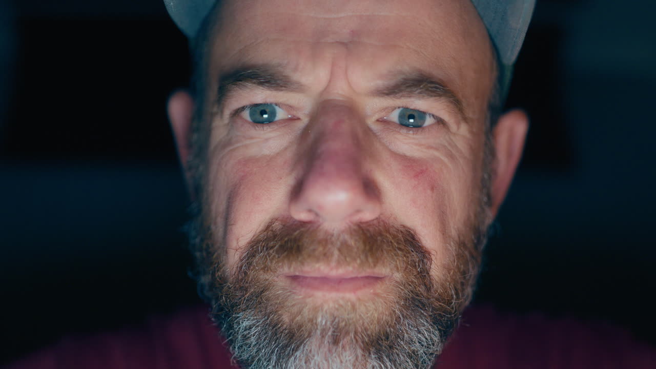Direct eye contact with creepy man whose face is illuminated by digital screen